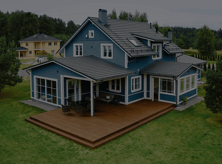 Blue house with wooden deck and trees.
