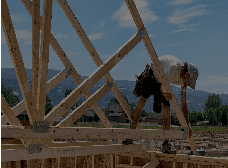 Worker building wooden house framework.