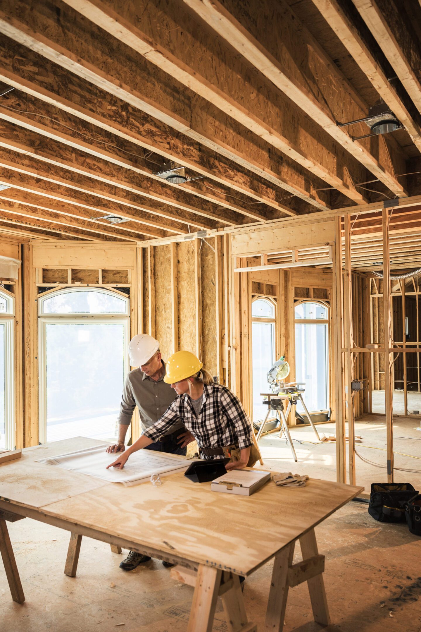 Construction workers reviewing plans in unfinished building.