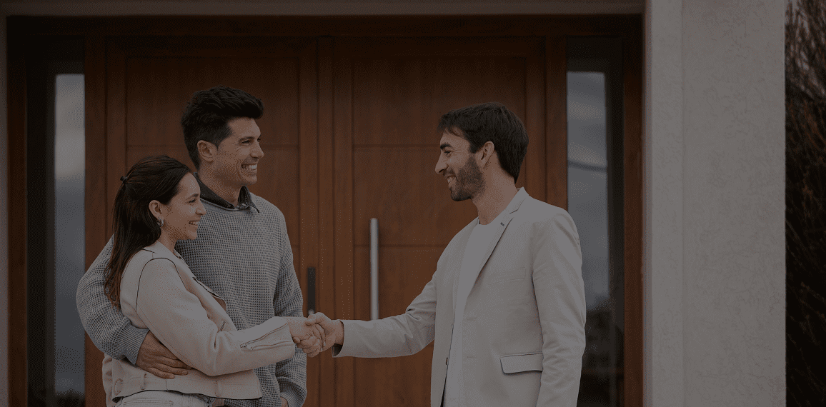 People shaking hands outside a house.