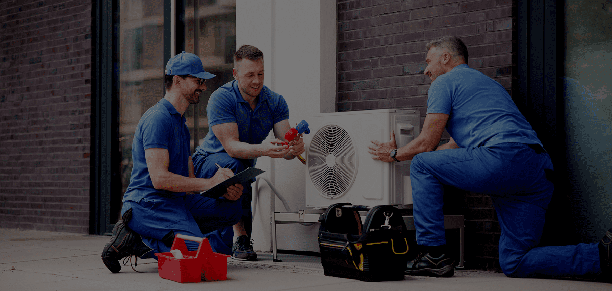 Technicians installing air conditioning unit outside.